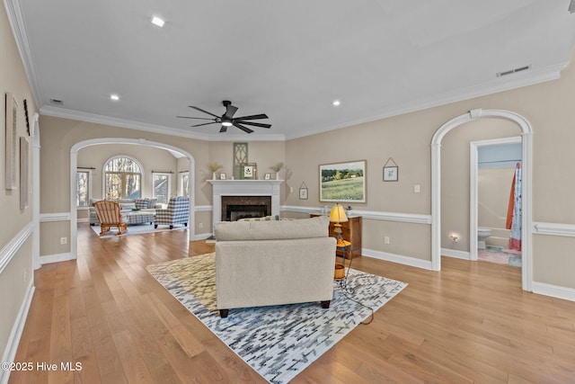 living room featuring ceiling fan, light wood-type flooring, and ornamental molding