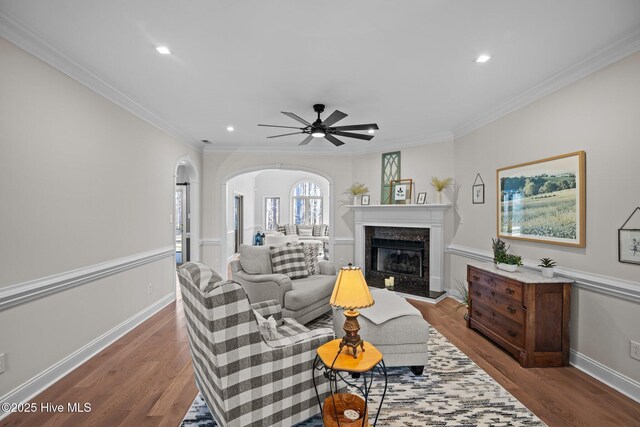 living area with arched walkways, a premium fireplace, visible vents, baseboards, and light wood-type flooring