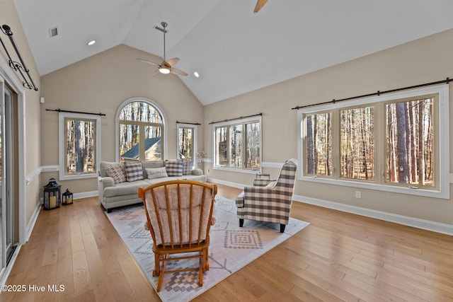 living room with ceiling fan, light hardwood / wood-style floors, and high vaulted ceiling