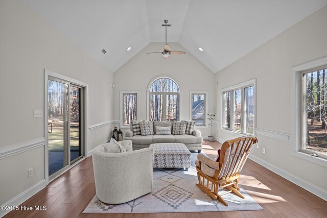 living room featuring light wood-style floors, baseboards, high vaulted ceiling, and a ceiling fan