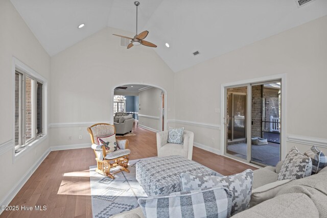 living room with arched walkways, ceiling fan, visible vents, and light wood-style flooring