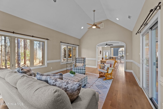 living room with ceiling fan, light hardwood / wood-style flooring, and high vaulted ceiling