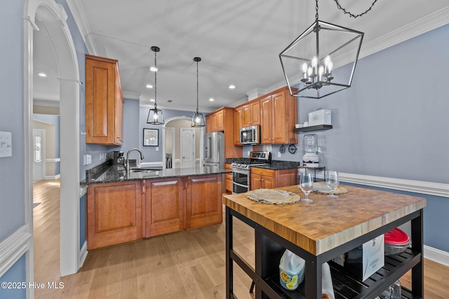 kitchen with sink, pendant lighting, a chandelier, appliances with stainless steel finishes, and ornamental molding