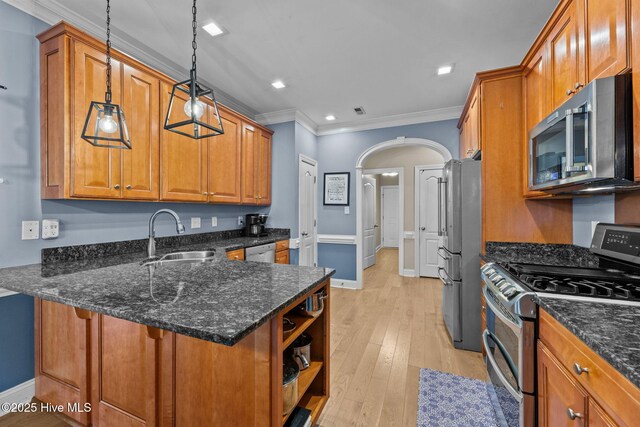 kitchen with brown cabinets, stainless steel appliances, hanging light fixtures, light wood-style flooring, and ornamental molding