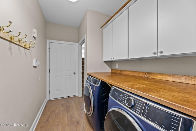 laundry room with cabinets, light wood-type flooring, and washer and clothes dryer