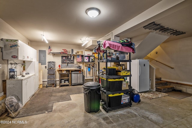 basement featuring a workshop area, white fridge, and electric panel