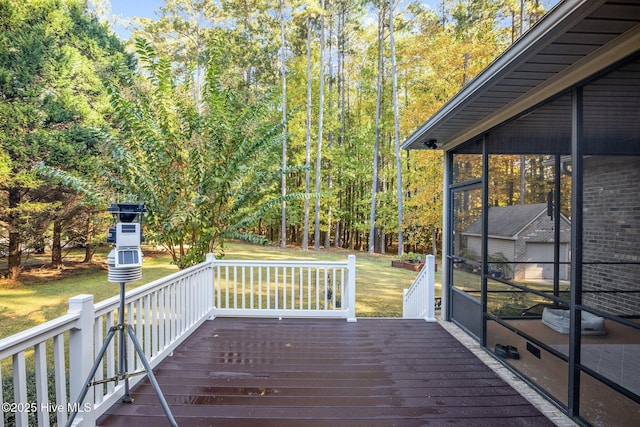 wooden terrace featuring a sunroom and a lawn