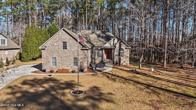 view of front facade featuring a front yard, brick siding, and driveway