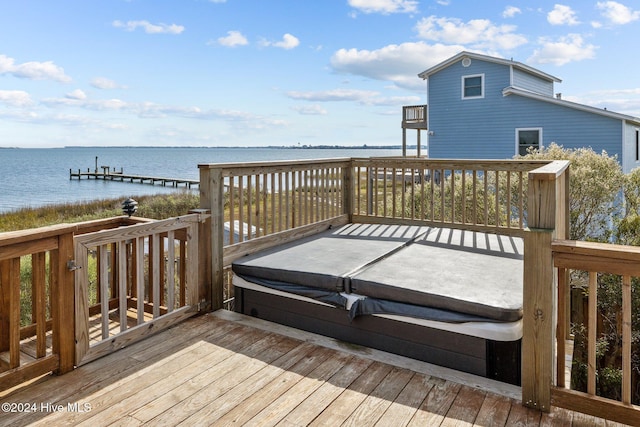 wooden terrace with a covered hot tub and a water view