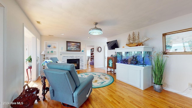 living room featuring a stone fireplace, a wealth of natural light, and light hardwood / wood-style flooring