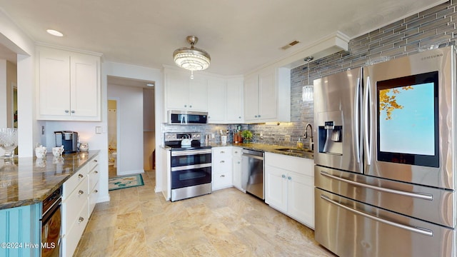 kitchen with sink, backsplash, dark stone counters, white cabinets, and appliances with stainless steel finishes