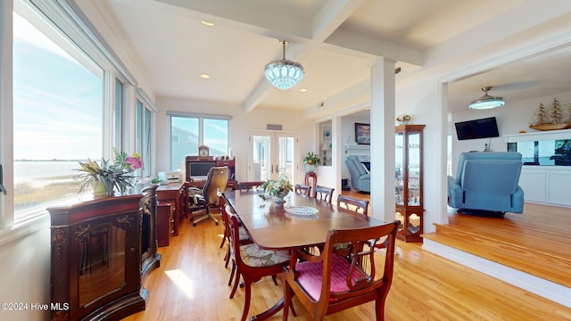 dining area featuring beam ceiling, french doors, a water view, and light wood-type flooring