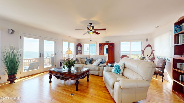 living room with a water view, a healthy amount of sunlight, and light wood-type flooring