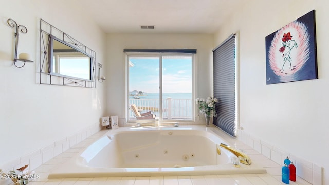 bathroom featuring tiled tub and a water view