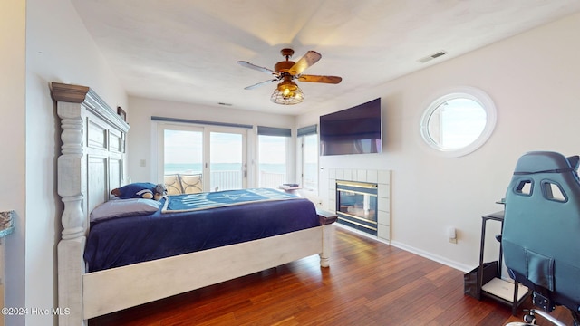 bedroom with ceiling fan, a fireplace, and dark wood-type flooring