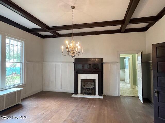 4290 W Church St, Farmville, NC 27828 - unfurnished living room with wood finished floors, beamed ceiling, an inviting chandelier, radiator, and coffered ceiling