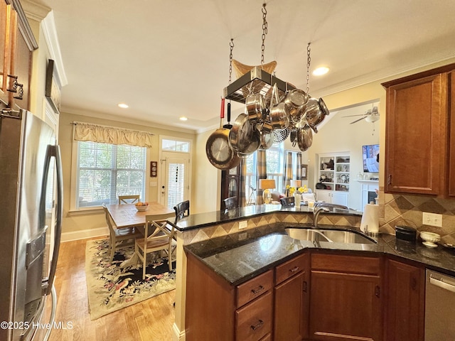 kitchen with a sink, stainless steel appliances, a peninsula, and ornamental molding