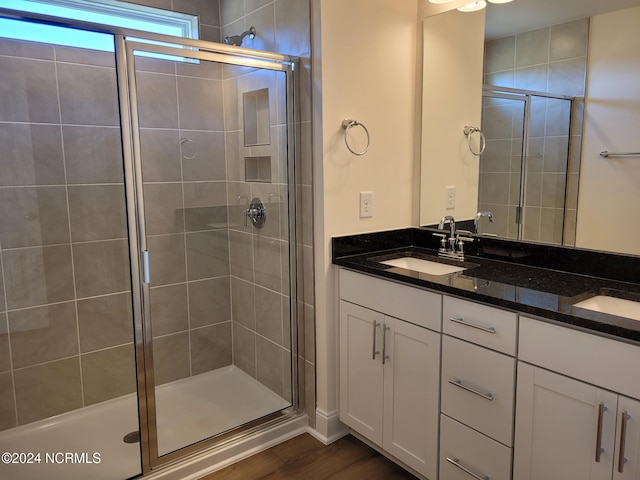 bathroom featuring a stall shower, double vanity, and wood finished floors