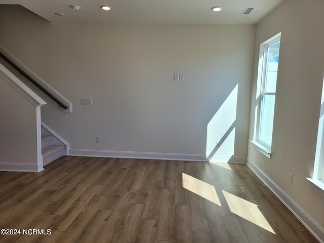 unfurnished living room with wood finished floors, stairs, baseboards, and recessed lighting