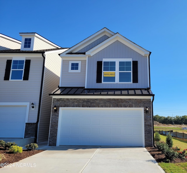 view of front of home featuring stone siding, a standing seam roof, a garage, and concrete driveway