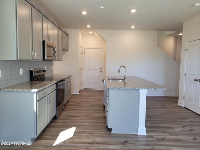 kitchen featuring stainless steel appliances, a sink, baseboards, wood finished floors, and gray cabinets