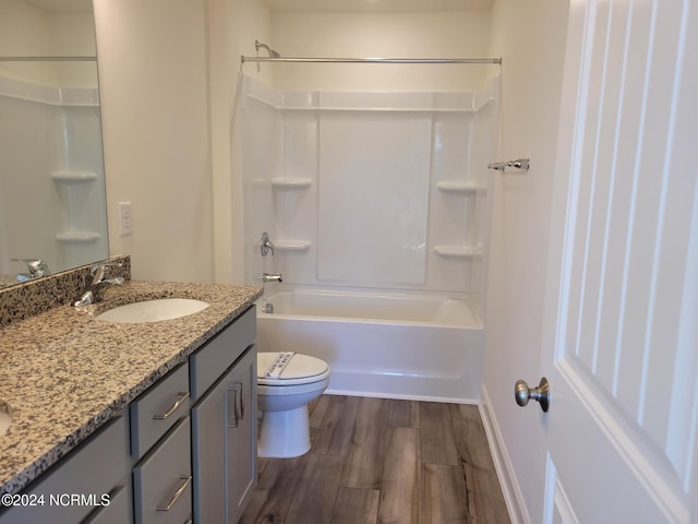 bathroom with toilet, double vanity, wood finished floors,  shower combination, and baseboards