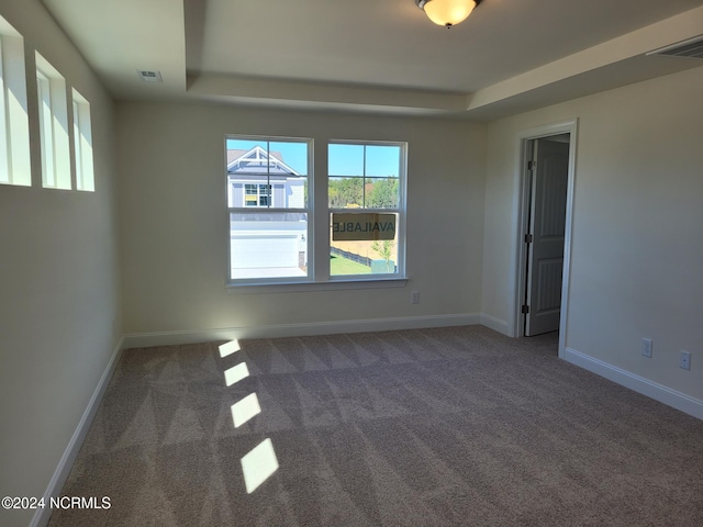 unfurnished room with a raised ceiling, carpet, and baseboards
