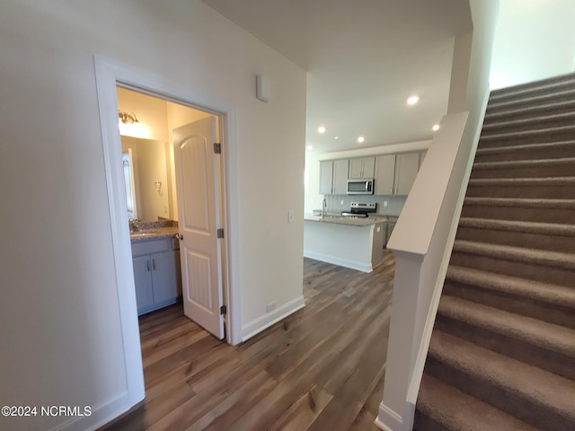 stairs with wood finished floors, recessed lighting, and baseboards