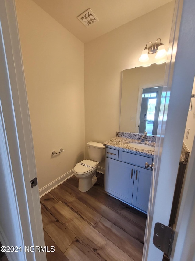 bathroom with wood finished floors, toilet, vanity, and baseboards