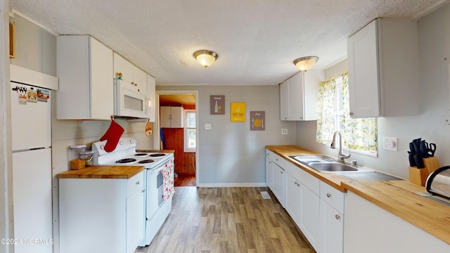 kitchen featuring butcher block counters, white cabinetry, and white appliances