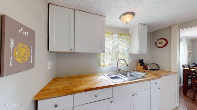 kitchen with white cabinets, sink, and butcher block countertops