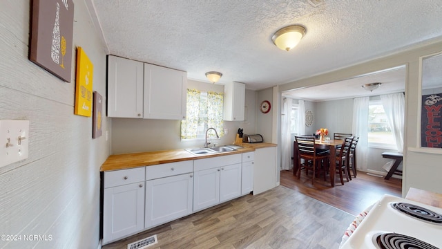 kitchen featuring white cabinets, wood counters, white stove, light hardwood / wood-style flooring, and sink