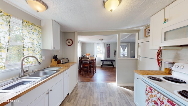 kitchen with a textured ceiling, white cabinetry, light wood-type flooring, sink, and white appliances