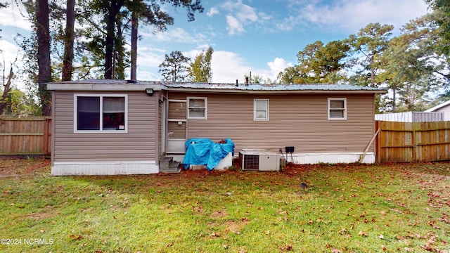 rear view of property with central air condition unit and a lawn