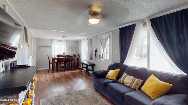 living room with a textured ceiling, dark wood-type flooring, and ceiling fan