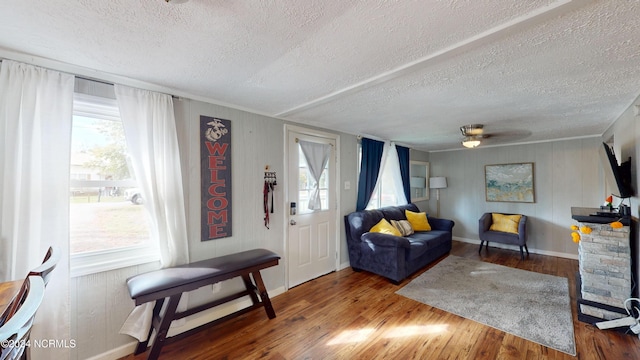 living room featuring a textured ceiling, wood-type flooring, a fireplace, and ceiling fan