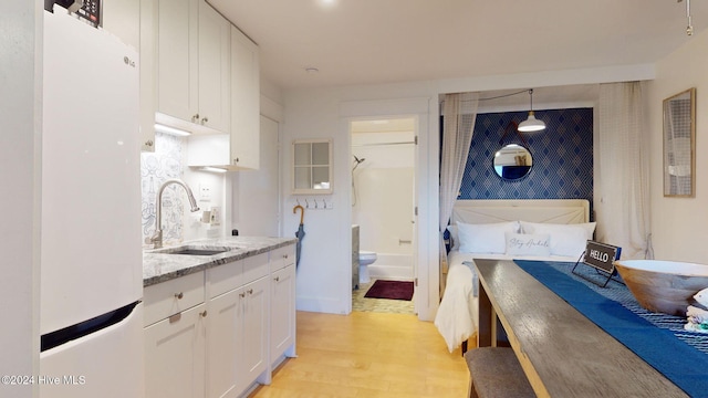 kitchen featuring white cabinetry, sink, decorative light fixtures, white fridge, and light wood-type flooring