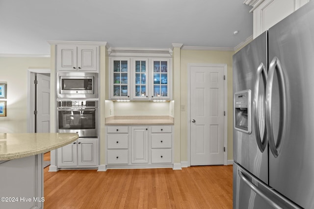 kitchen featuring stainless steel appliances, ornamental molding, light hardwood / wood-style flooring, and white cabinets