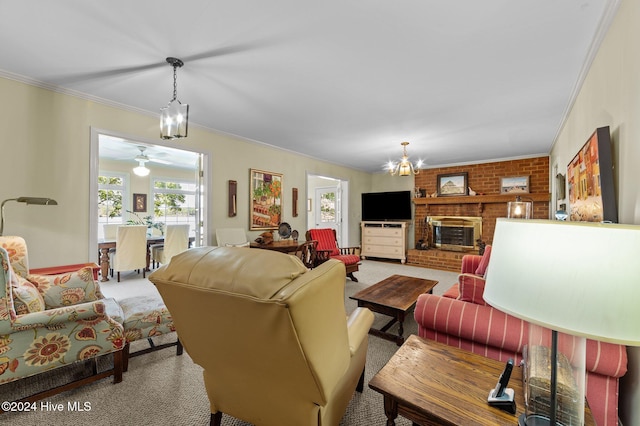 carpeted living room with crown molding, a brick fireplace, and ceiling fan with notable chandelier