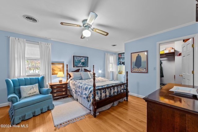 bedroom with a closet, a spacious closet, light wood-type flooring, and ceiling fan