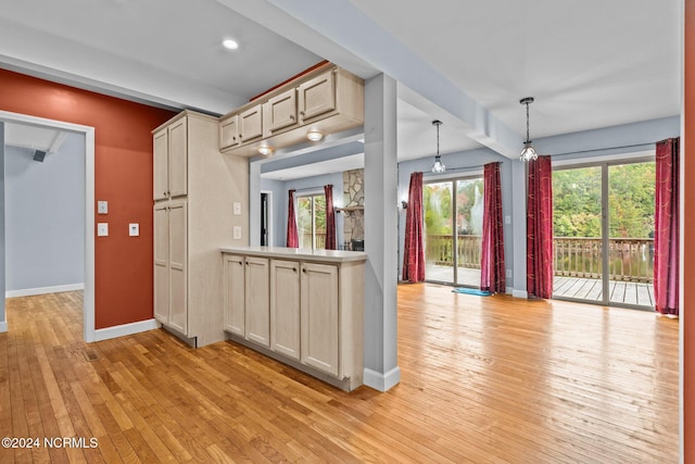 kitchen with light hardwood / wood-style floors, beamed ceiling, pendant lighting, and light brown cabinets