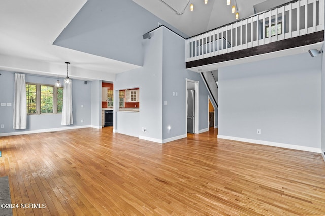 unfurnished living room featuring light hardwood / wood-style flooring and a towering ceiling