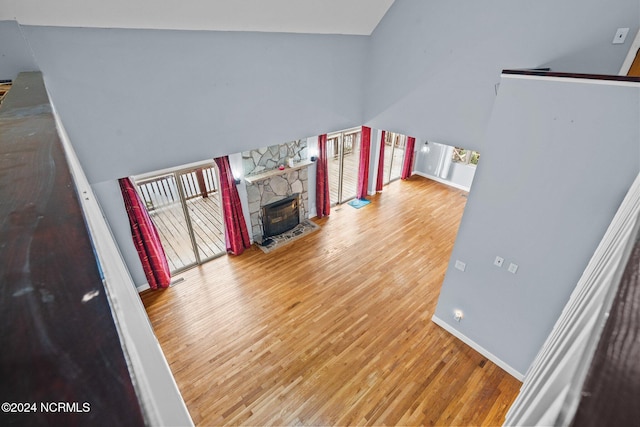 living room featuring a stone fireplace, hardwood / wood-style flooring, and a high ceiling