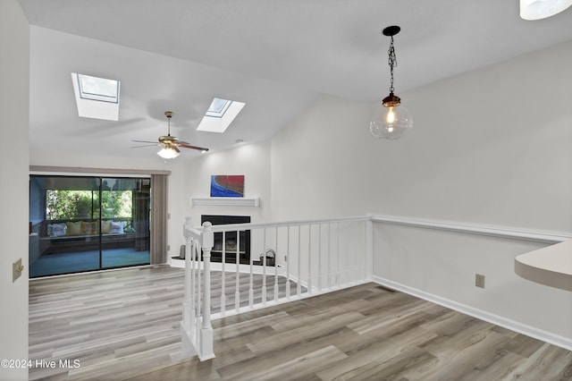 interior space with hardwood / wood-style flooring, ceiling fan, and vaulted ceiling with skylight