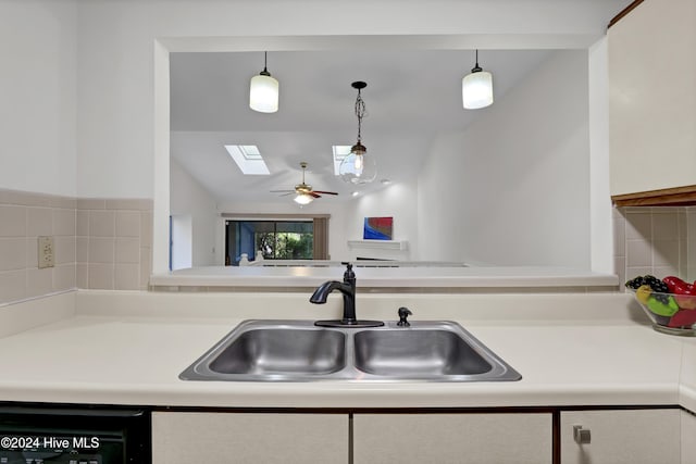 kitchen with white cabinetry, vaulted ceiling with skylight, sink, and hanging light fixtures