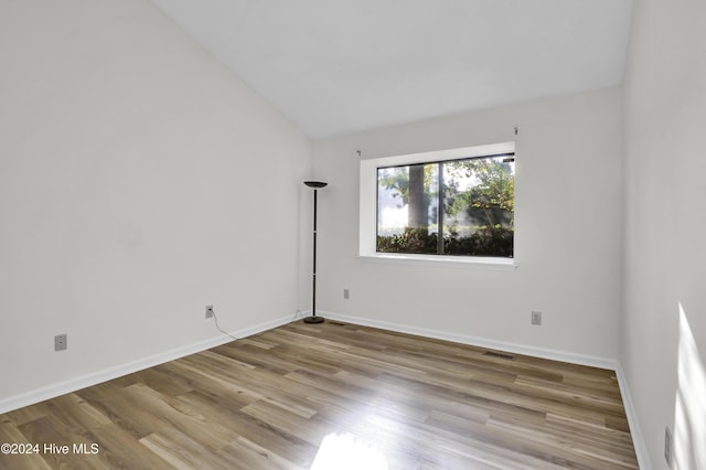 unfurnished room featuring vaulted ceiling and light hardwood / wood-style flooring