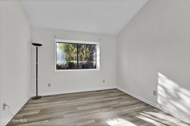 unfurnished room featuring lofted ceiling and light hardwood / wood-style flooring