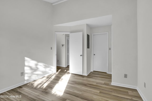 spare room featuring electric panel and light wood-type flooring