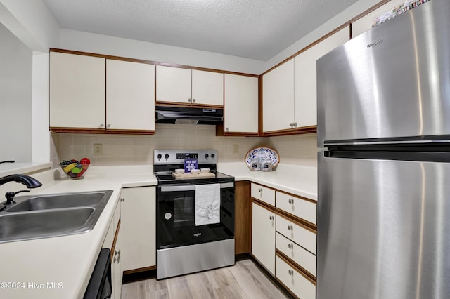 kitchen with extractor fan, appliances with stainless steel finishes, white cabinetry, sink, and backsplash