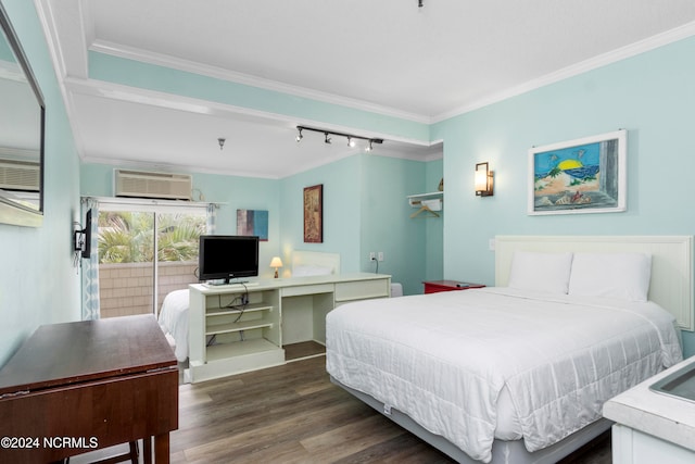 bedroom with built in desk, an AC wall unit, dark wood-type flooring, crown molding, and track lighting